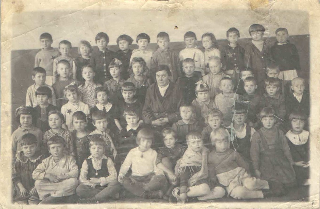 Оля Филатова — с бантиком возле учительницы. Первый класс. 1947 год